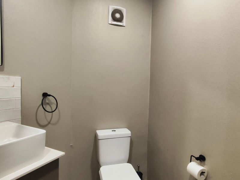 A modern bathroom featuring a vessel sink with a wall-mounted faucet, subway tile backsplash, and a white toilet.