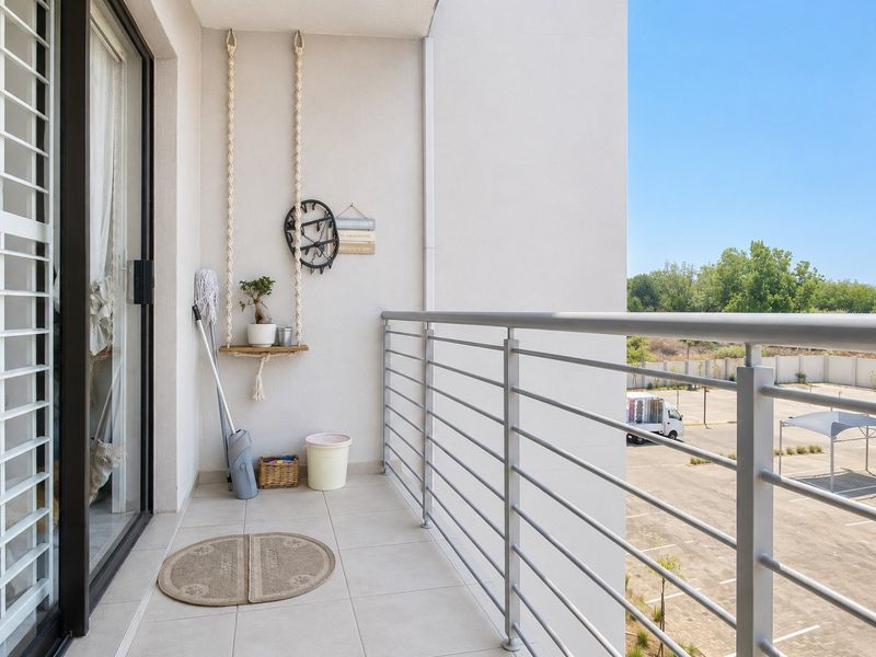 A clean, modern balcony featuring tiled flooring and a secure metal balustrade, offering an open view of the surrounding area.