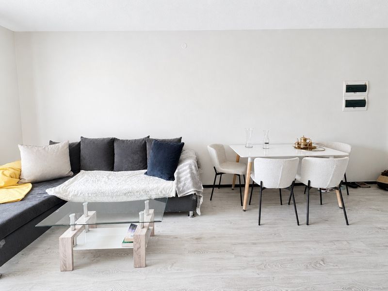An open-plan living and dining area featuring light-toned laminate flooring and neutral wall finishes, providing a versatile space for relaxation and dining.