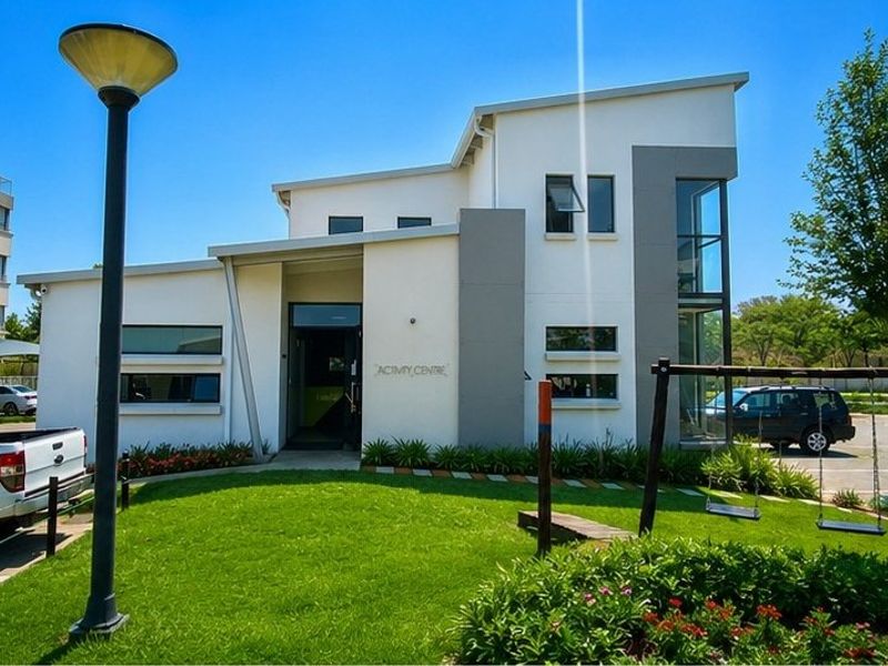 A modern apartment complex activity centre featuring a clean architectural design, large windows, and well-maintained surrounding lawn and landscaping.