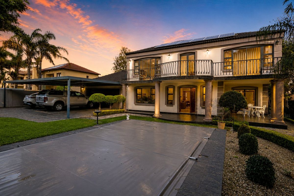 A well-maintained two-story residence featuring a covered swimming pool, a spacious balcony with iron railings, solar panels, and a convenient carport.