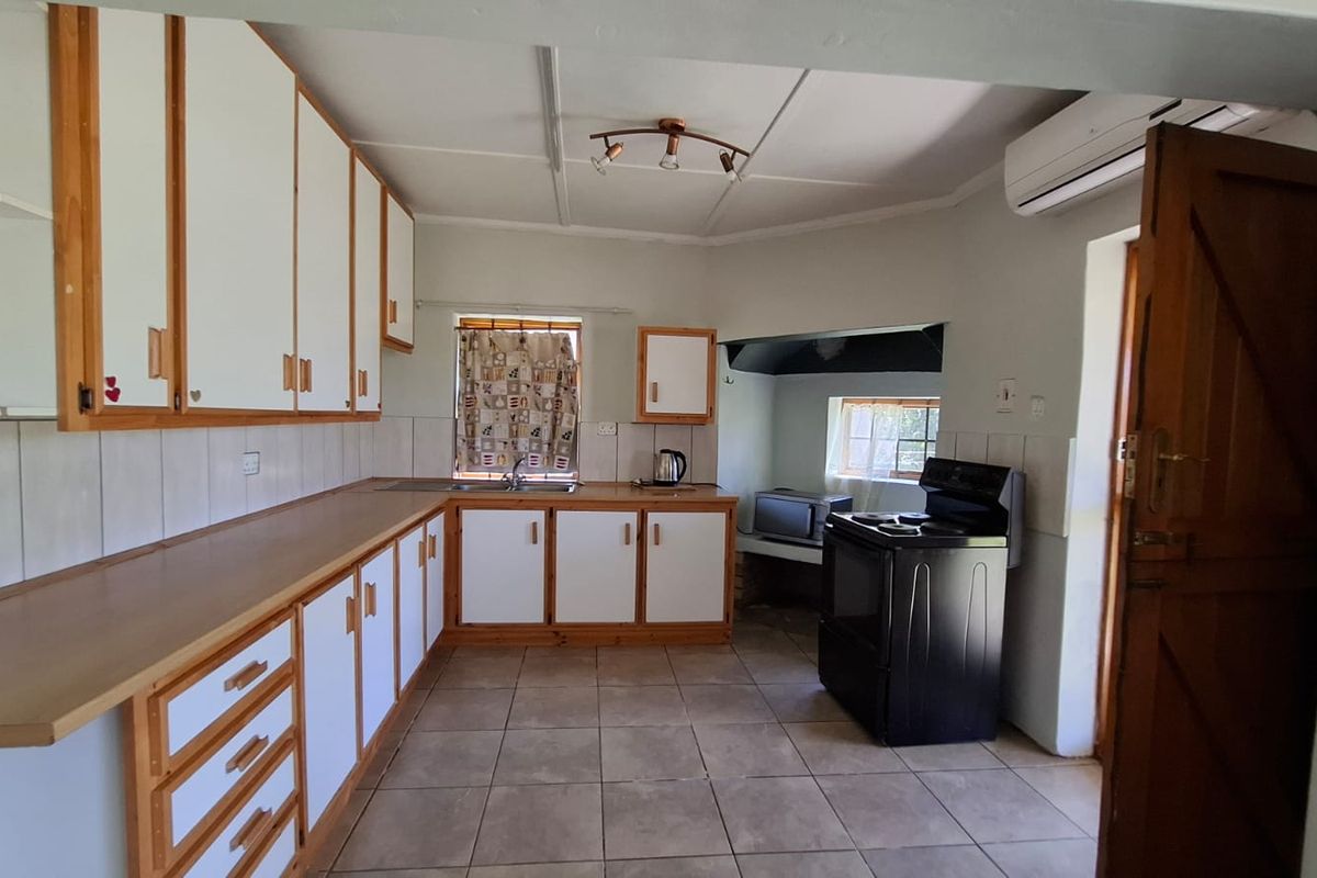 A functional kitchen featuring extensive built-in cabinetry, tiled flooring, a double sink, and an integrated air conditioning unit.