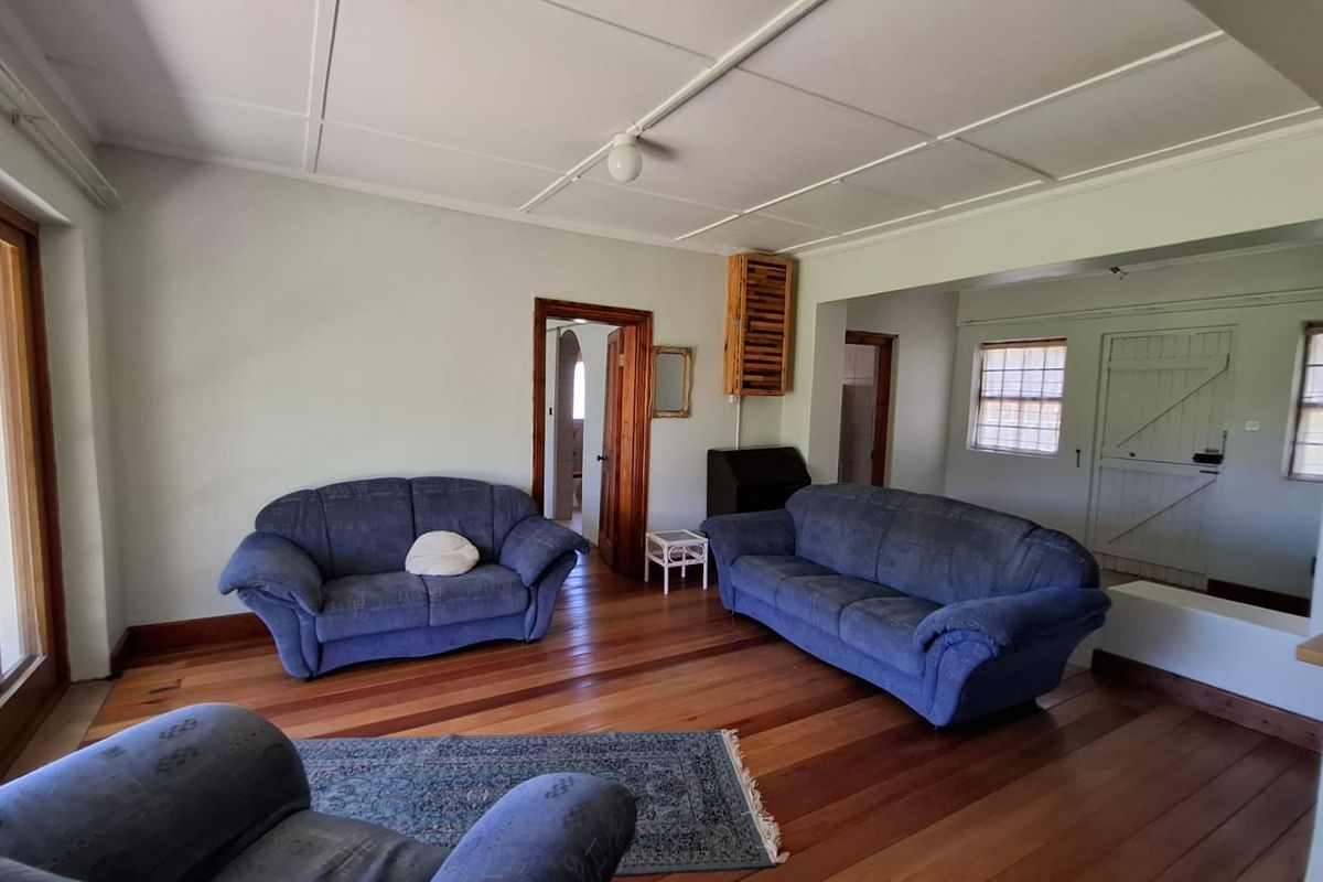 Spacious living area featuring original hardwood flooring, exposed beam ceiling, and direct access to the outdoor patio through sliding glass doors.