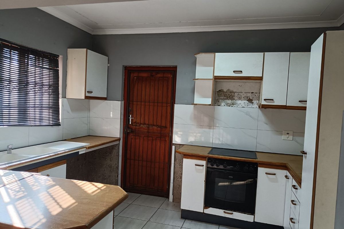 A functional kitchen featuring built-in cabinetry, laminate countertops, a built-in oven with hob, and tiled flooring, requiring cosmetic updates to modernize the space.
