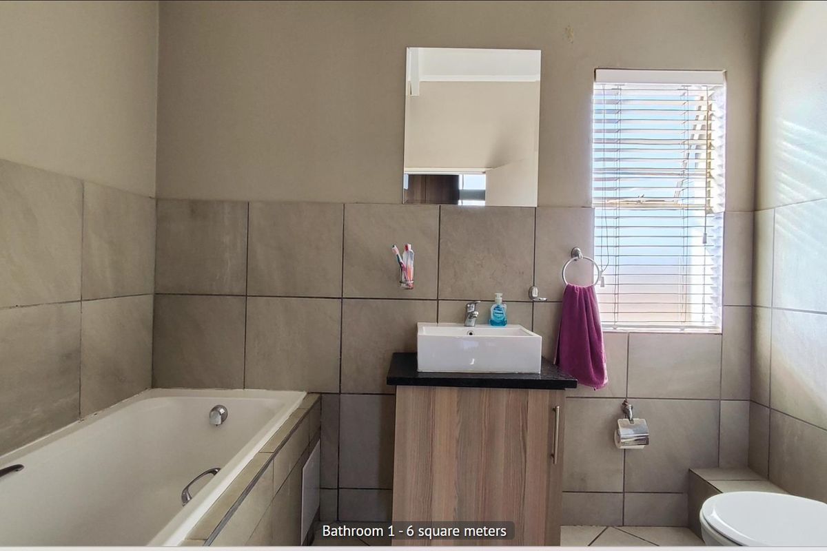 A functional bathroom featuring a bathtub, a modern vessel sink on a vanity cabinet, and neutral wall tiling.