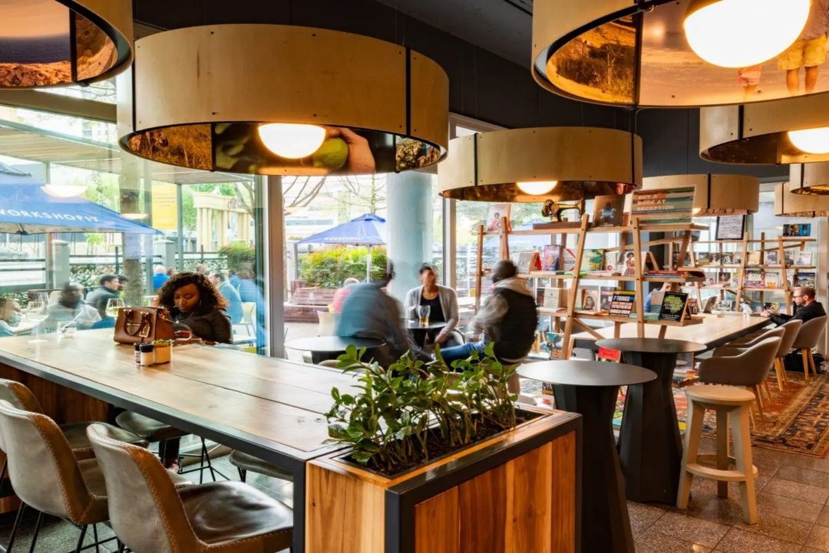 Modern open-plan commercial space featuring floor-to-ceiling windows, tiled flooring, and unique circular pendant lighting, creating a bright and inviting atmosphere.