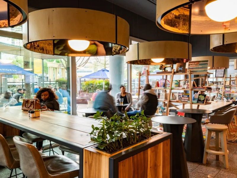 Modern open-plan commercial space featuring floor-to-ceiling windows, tiled flooring, and unique circular pendant lighting, creating a bright and inviting atmosphere.