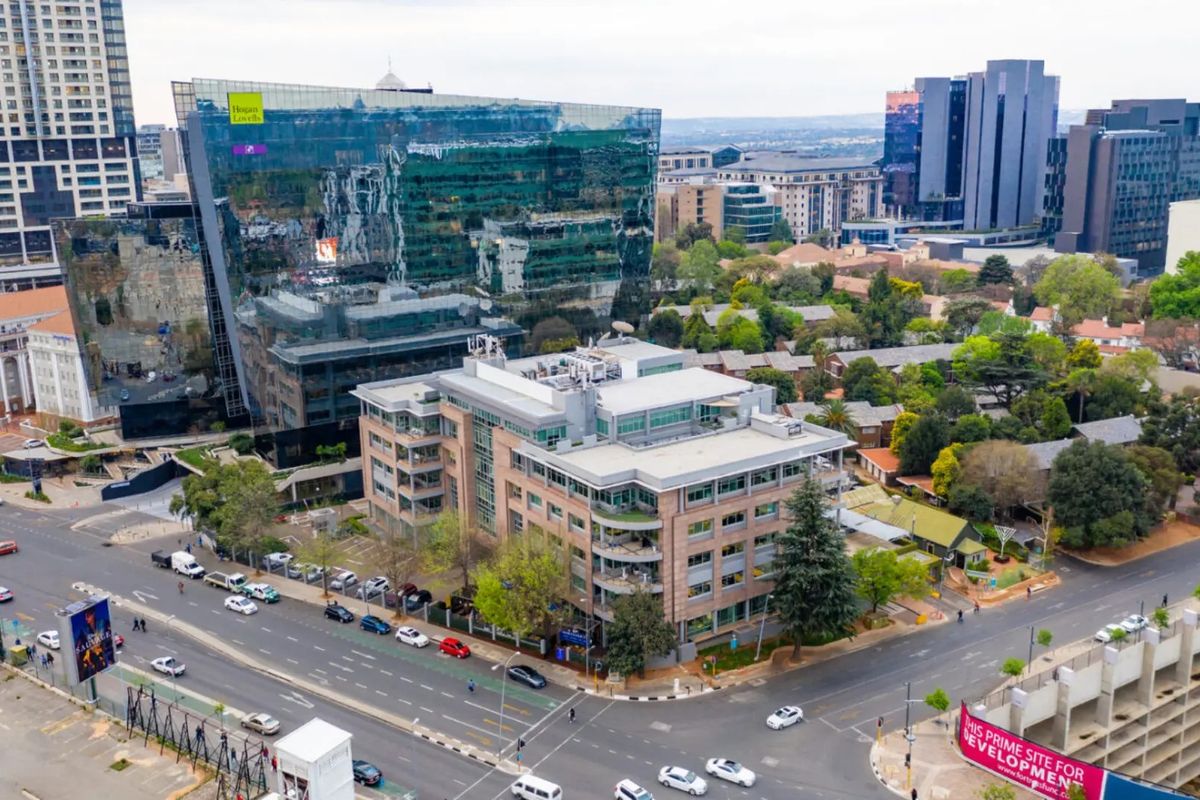 Aerial view of a commercial office building situated at a street intersection, surrounded by urban infrastructure and mature trees.