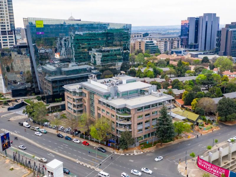 Aerial view of a commercial office building situated at a street intersection, surrounded by urban infrastructure and mature trees.