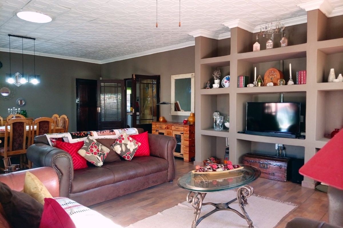 Spacious living room featuring a large built-in shelving unit, decorative ceiling tiles, crown molding, and laminate flooring, creating a warm and inviting atmosphere.