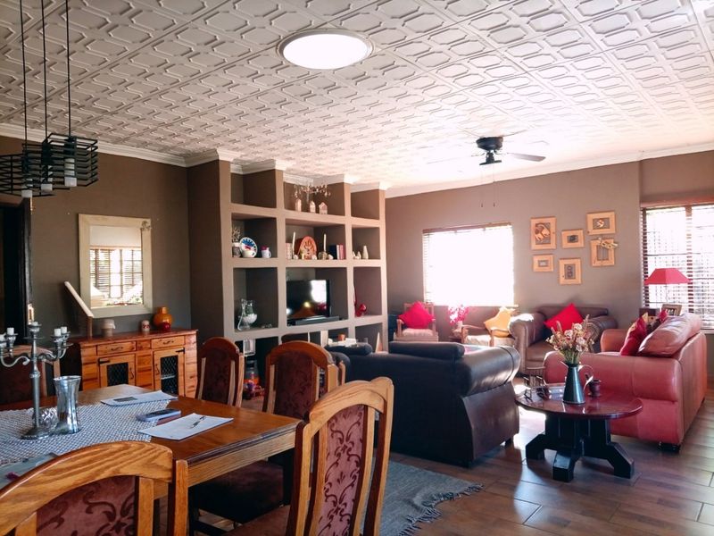 Spacious open-plan living and dining area featuring a decorative coffered ceiling, built-in shelving unit, and tiled flooring throughout.