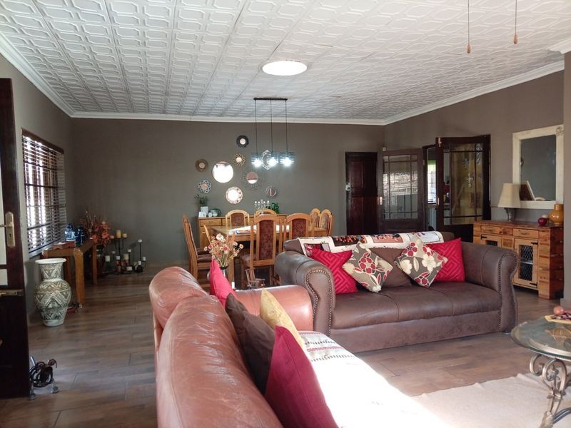 Spacious open-plan living and dining area featuring tiled flooring, a decorative coffered ceiling, and classic french doors leading to adjacent spaces.