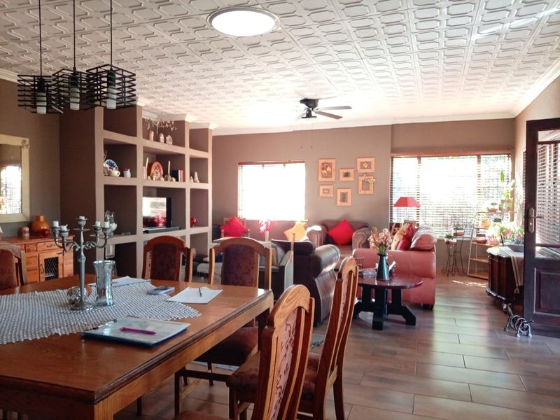 Spacious open-plan living and dining area featuring tiled floors, a decorative ceiling, and a large built-in shelving unit.