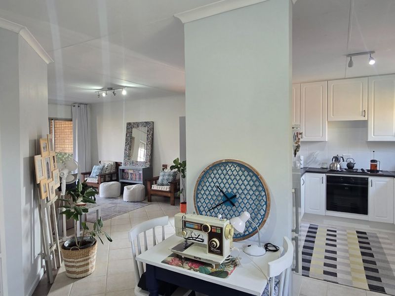 Open-plan living and kitchen area featuring white cabinetry, integrated oven, hob, and tiled flooring, creating a bright and functional combined living space.