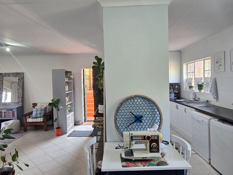 Open plan living and kitchen area featuring tiled flooring, white cabinetry, and laminate countertops in a functional, well-lit layout.