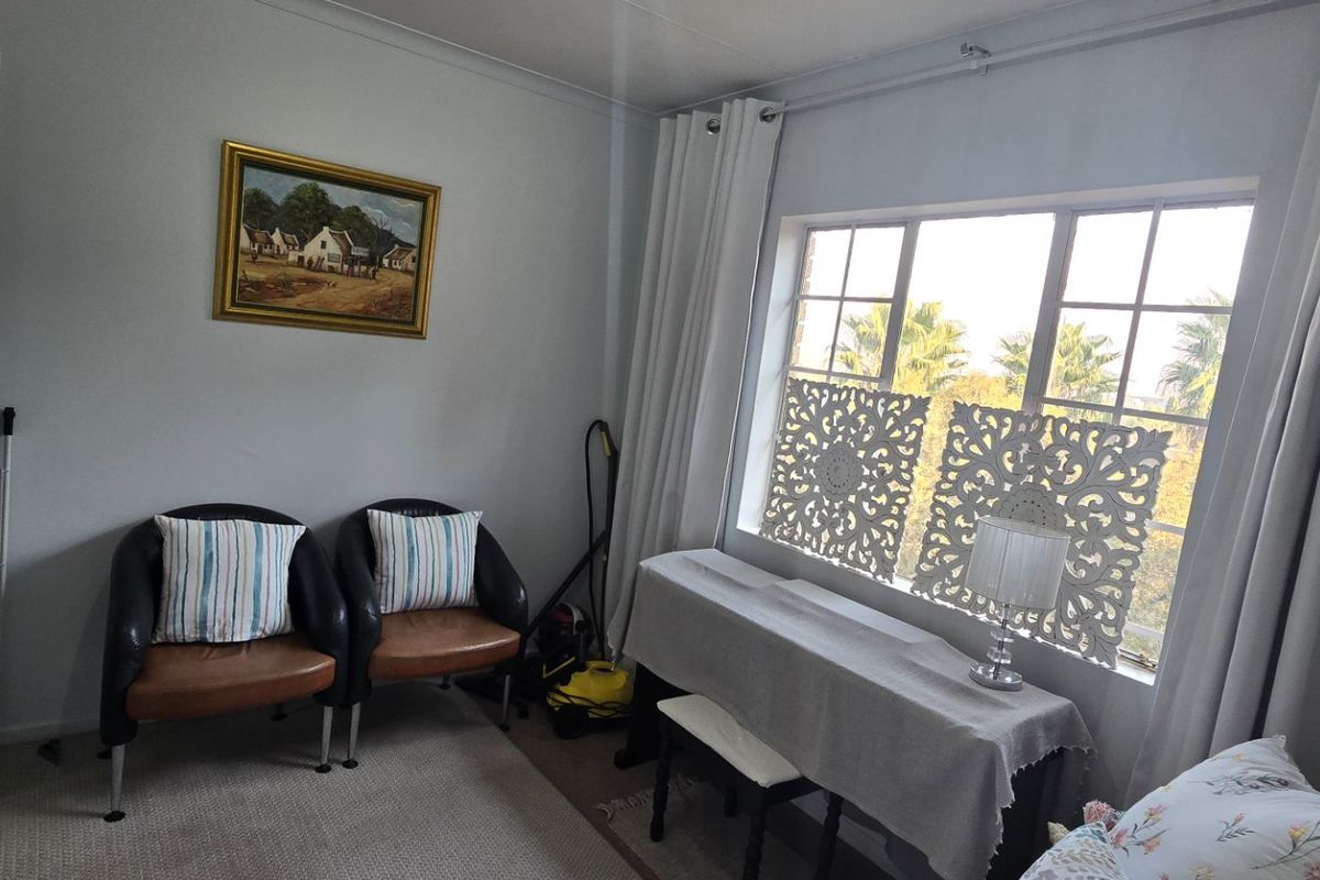 A bedroom featuring carpeted flooring and a large multi-pane window with curtain tracks, providing natural light and a view of the exterior.