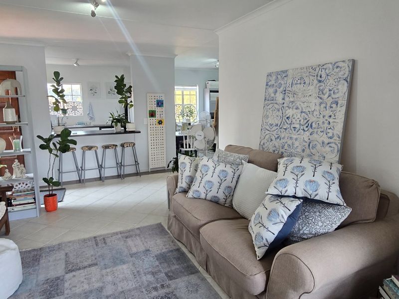 An open-plan living and kitchen area featuring tiled flooring, a breakfast bar, and coved cornicing, creating a connected and functional living space.
