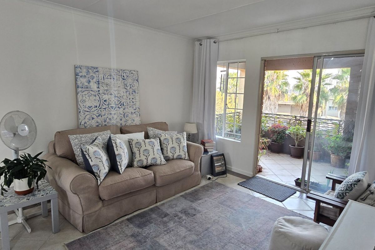 A cozy living room featuring tiled flooring and a sliding glass door that provides direct access to an outdoor patio area.