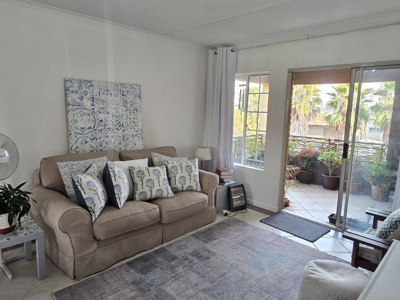 A cozy living room featuring tiled flooring and a sliding glass door that provides direct access to an outdoor patio area.