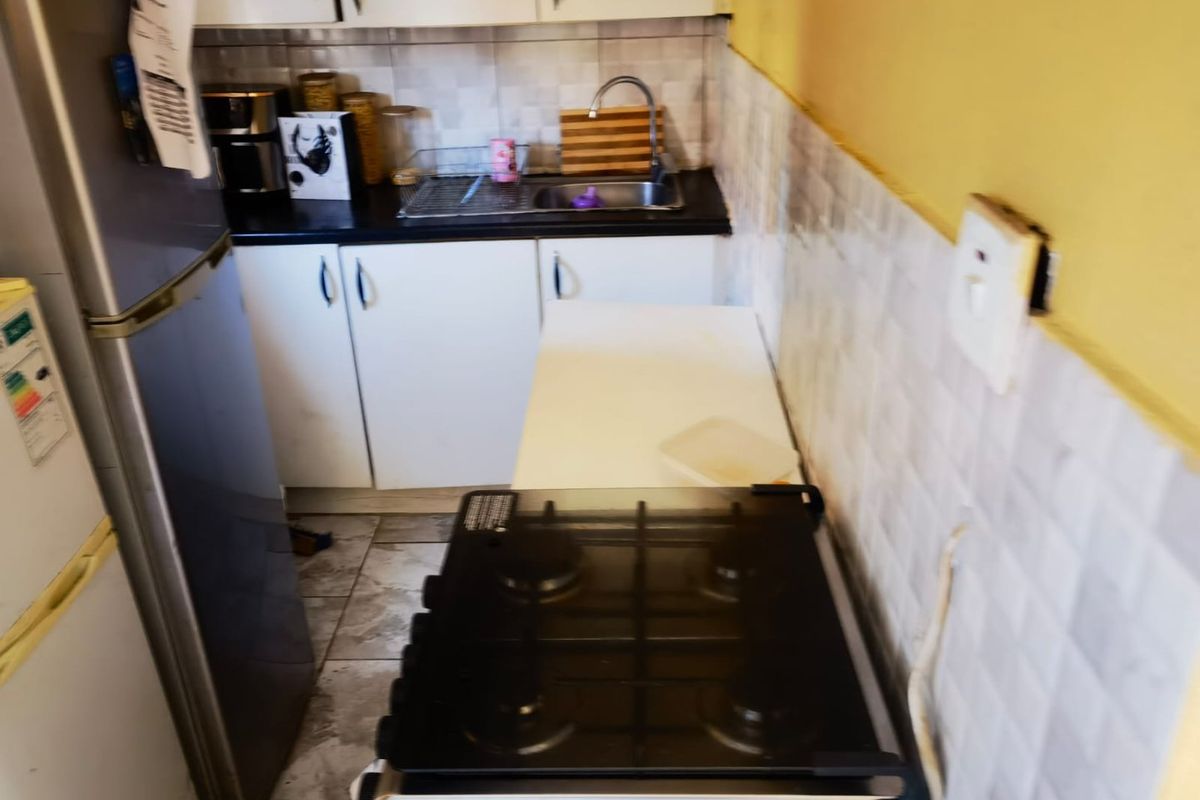 Compact kitchen featuring built-in cabinetry, a gas hob, and tiled backsplash. The space requires minor repairs to electrical fixtures and cosmetic updates.