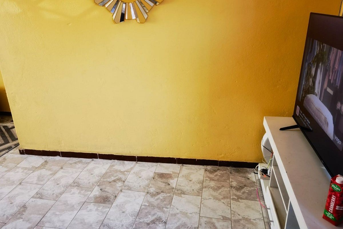 A living room area featuring tiled flooring and a bright yellow wall finish.