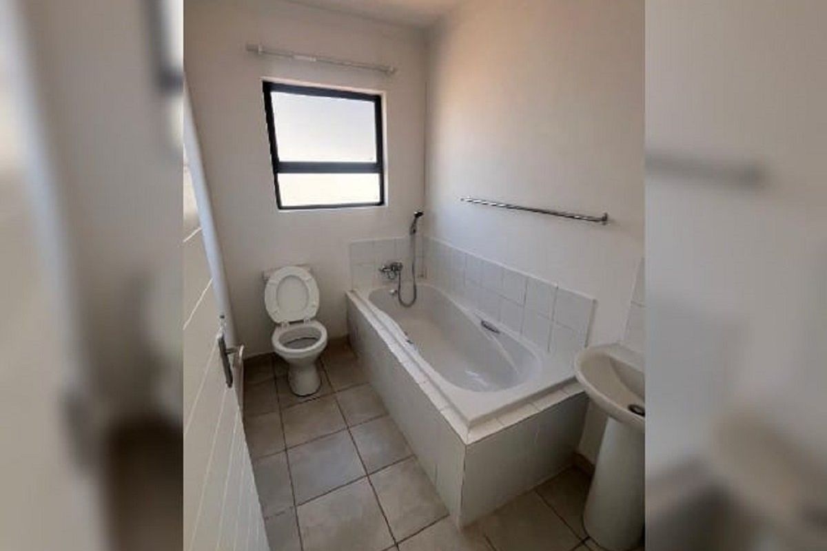 A functional bathroom featuring a pedestal basin, a built-in bathtub with shower attachment, and tiled flooring.