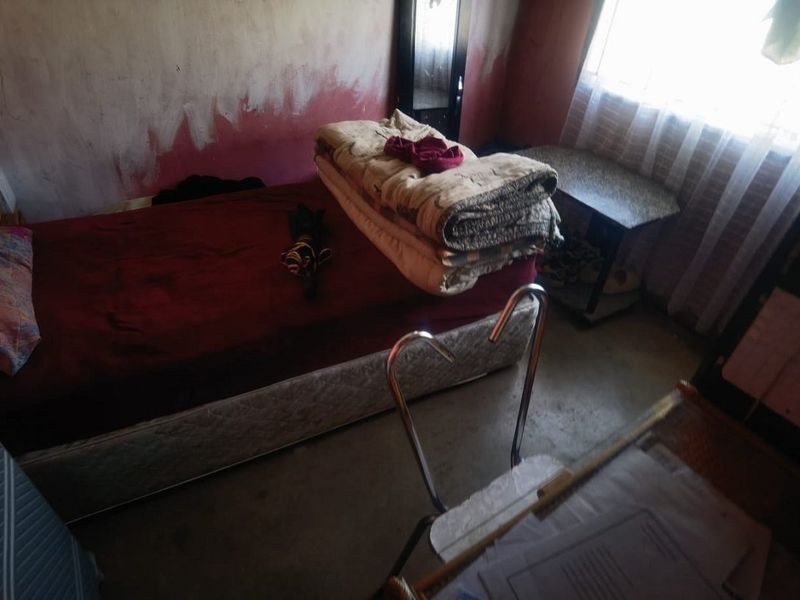 A bedroom featuring basic finishes with visible wall surface deterioration, requiring cosmetic updates and repairs to improve the overall condition of the space.