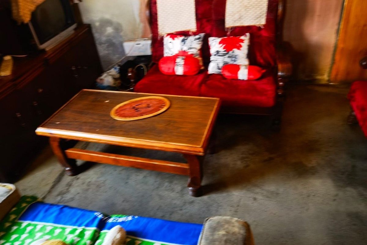 A living room area showing signs of significant wear on the walls and flooring, requiring cosmetic updates and refurbishment.