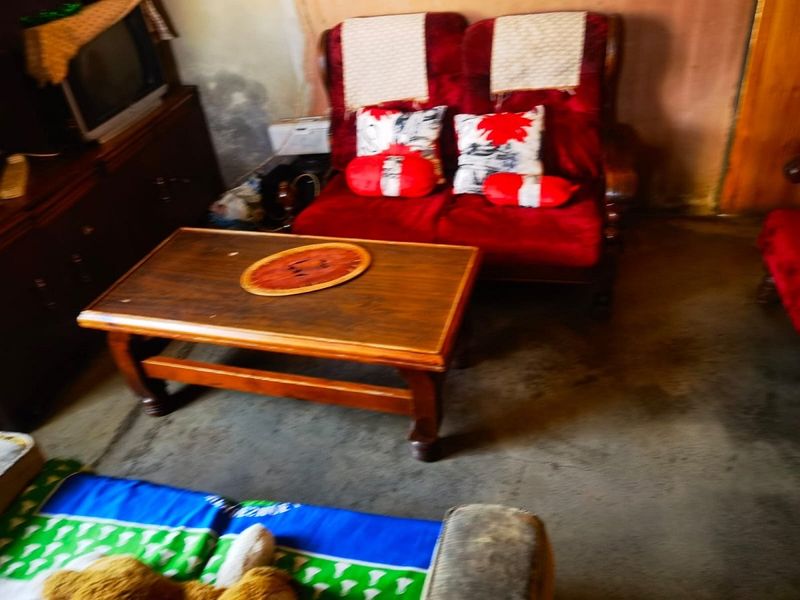 A living room area showing signs of significant wear on the walls and flooring, requiring cosmetic updates and refurbishment.