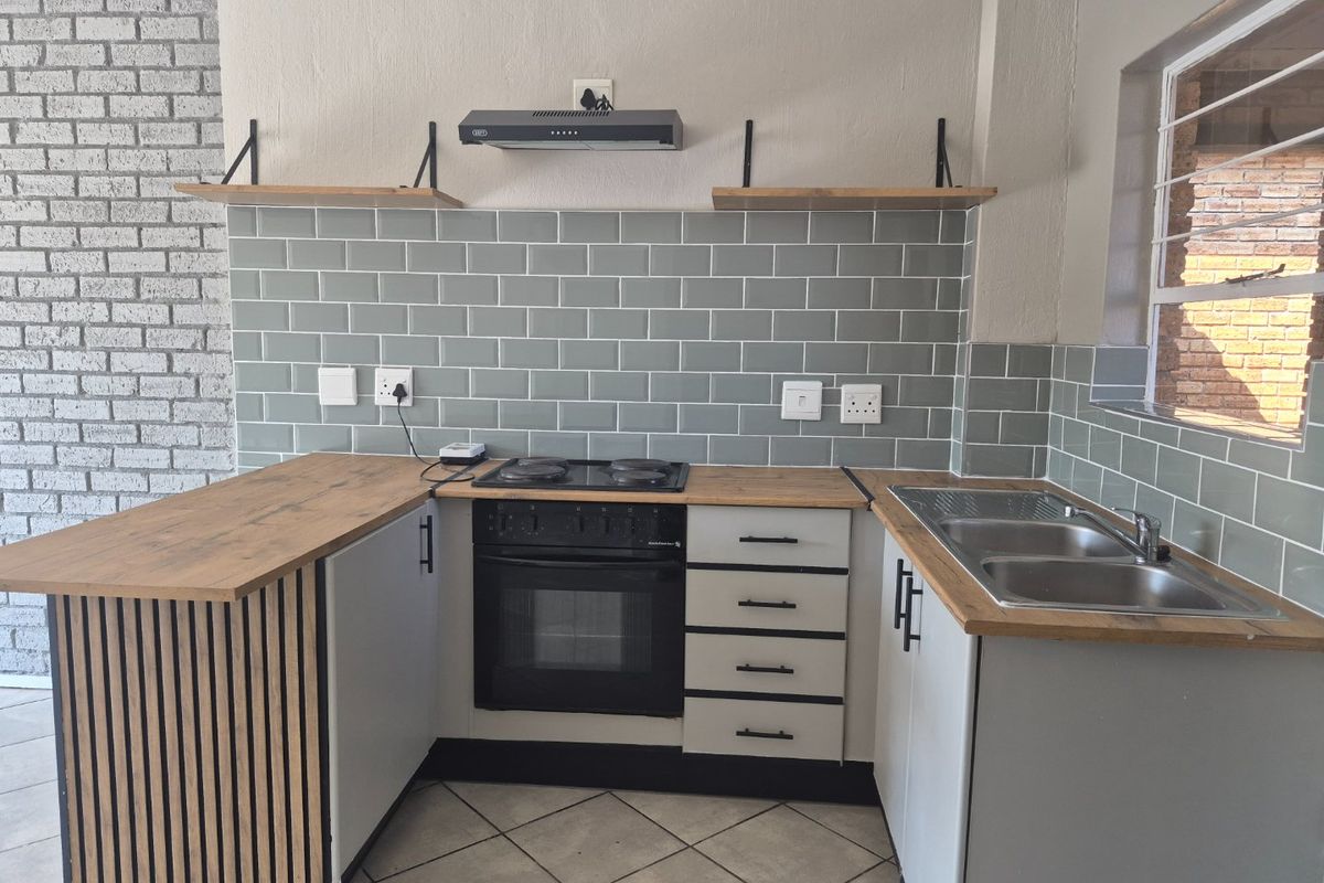 Modern kitchen featuring subway tile backsplash, wooden countertops, built-in oven with hob, extractor fan, and a functional double bowl sink.
