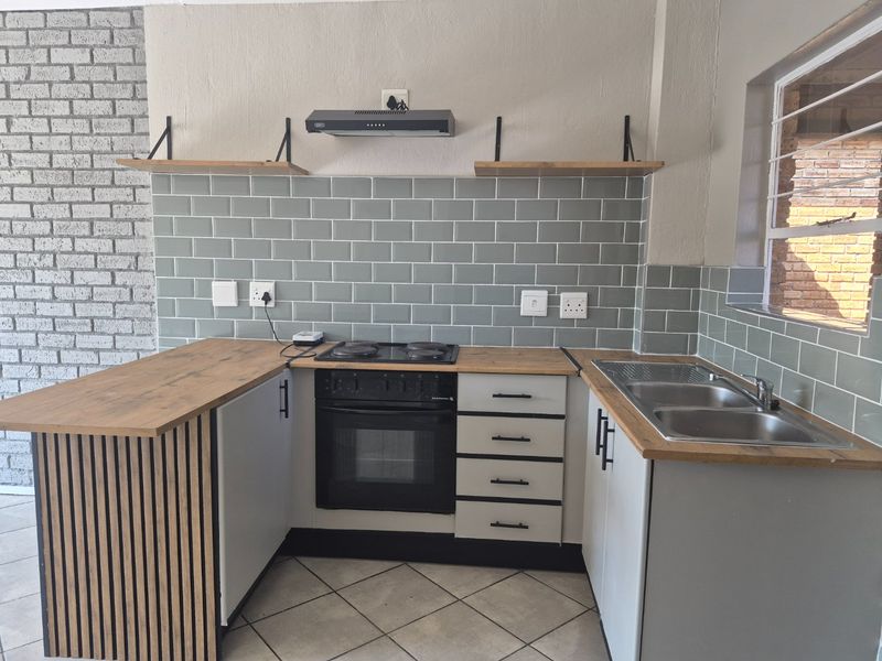 Modern kitchen featuring subway tile backsplash, wooden countertops, built-in oven with hob, extractor fan, and a functional double bowl sink.