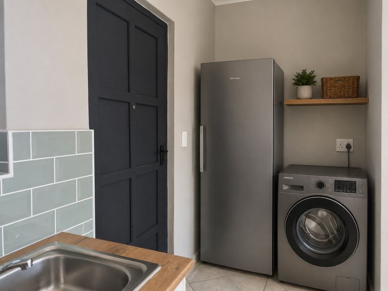 A functional laundry area featuring a stainless steel sink, subway tile backsplash, wooden countertop, and dedicated space for appliances.