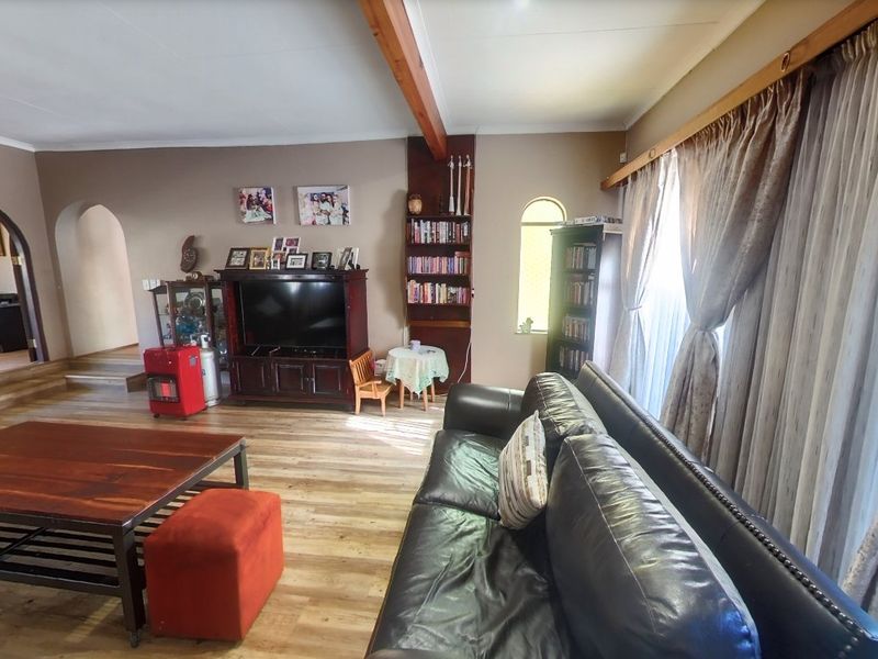 Spacious living room featuring laminate flooring, an exposed timber beam, and an arched doorway leading to an adjacent room.