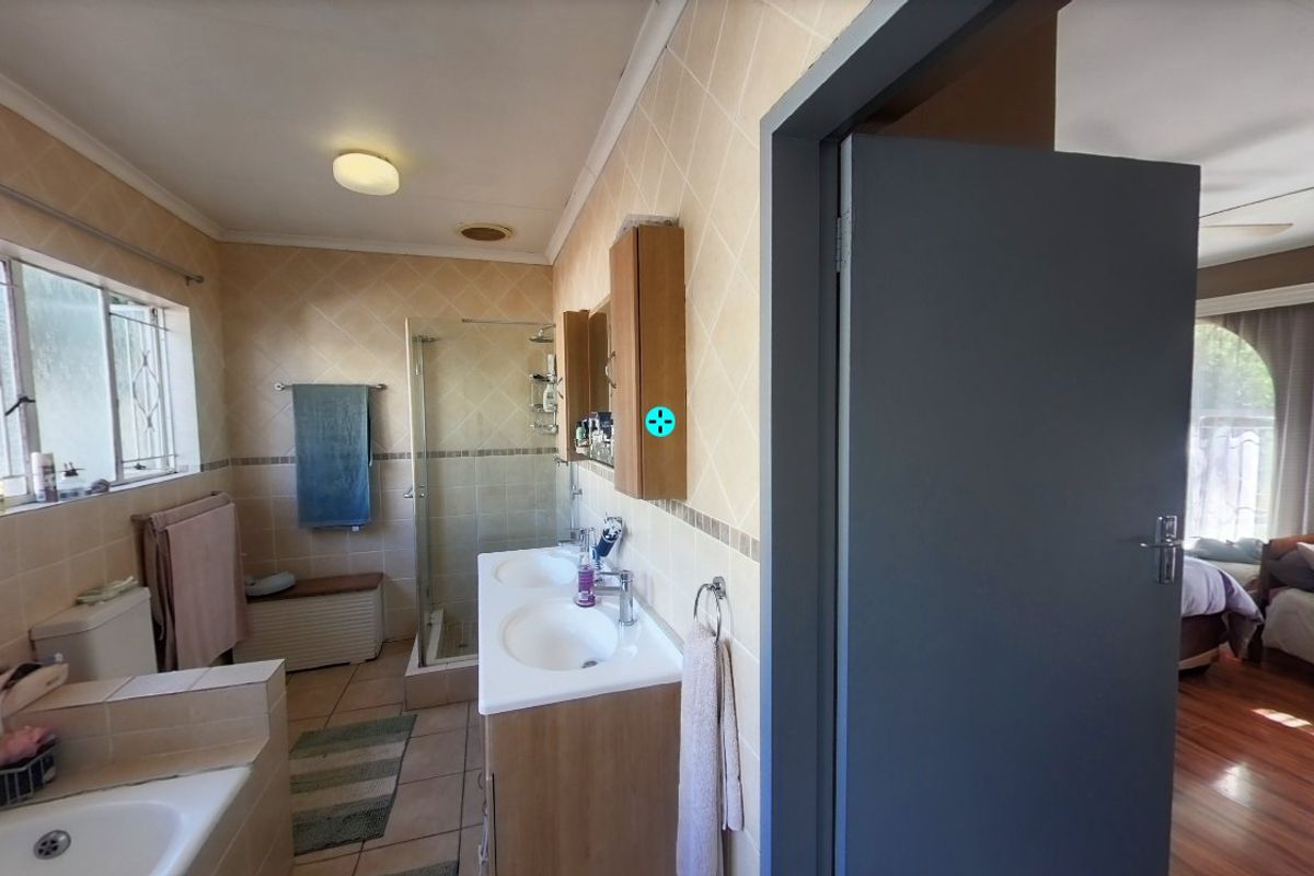A functional bathroom featuring a double vanity, shower enclosure, and built-in bathtub with neutral wall tiling.
