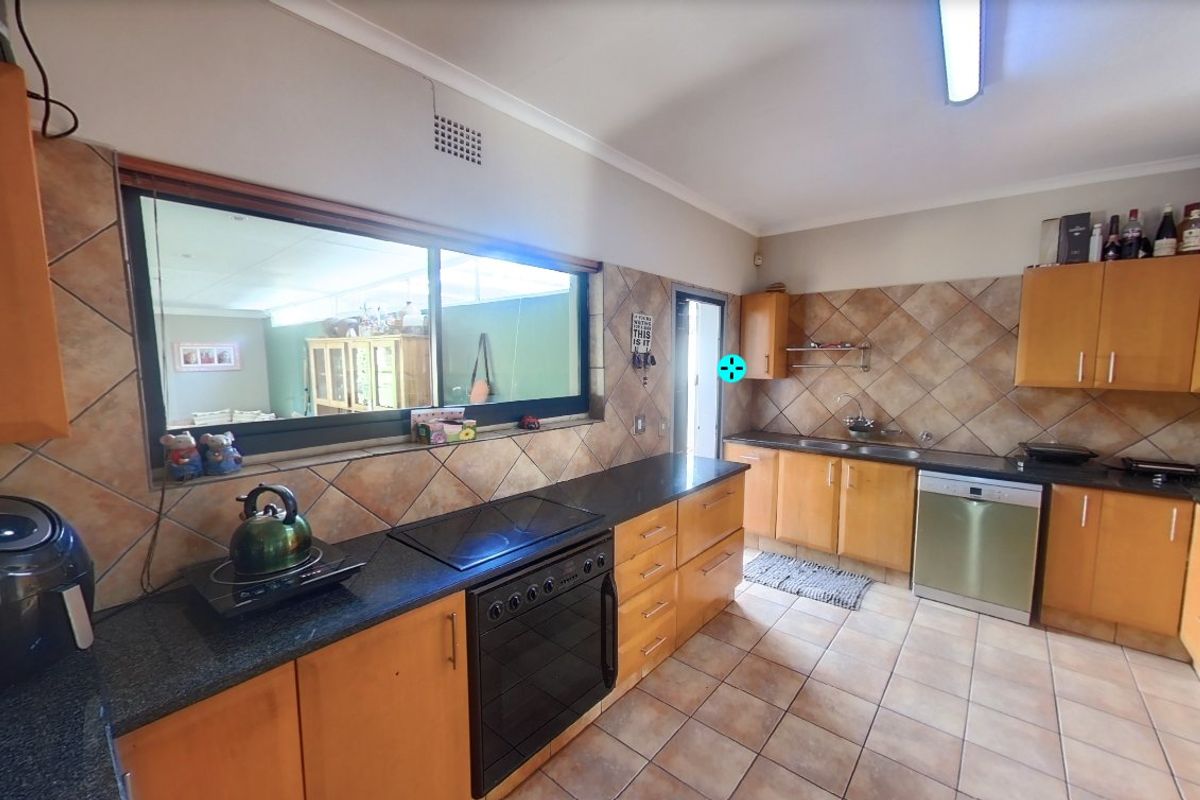 A functional kitchen featuring wooden cabinetry, granite countertops, a built-in oven, hob, and tiled finishes throughout.