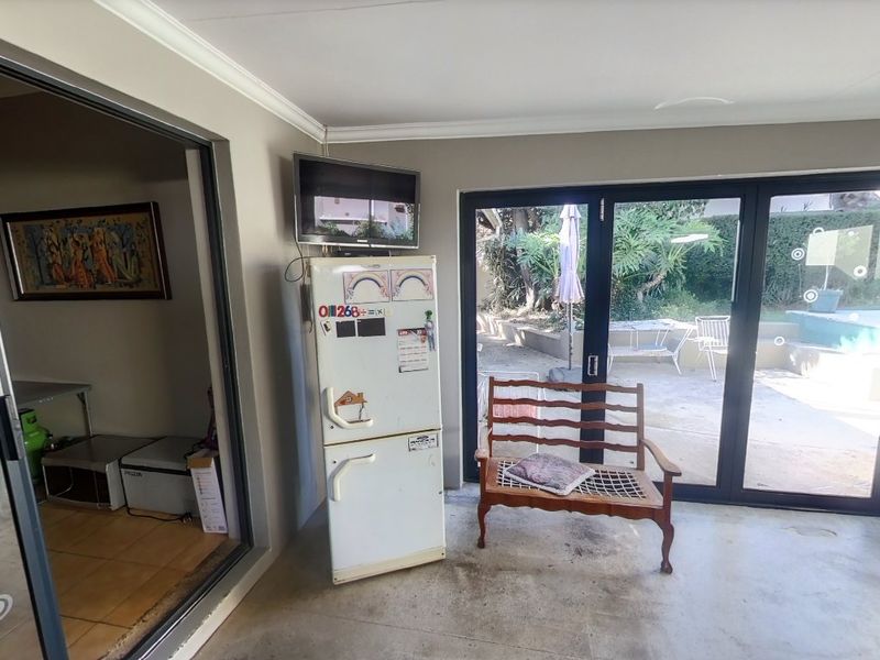 A covered patio area featuring large sliding glass doors that provide seamless access to the outdoor garden and pool space.