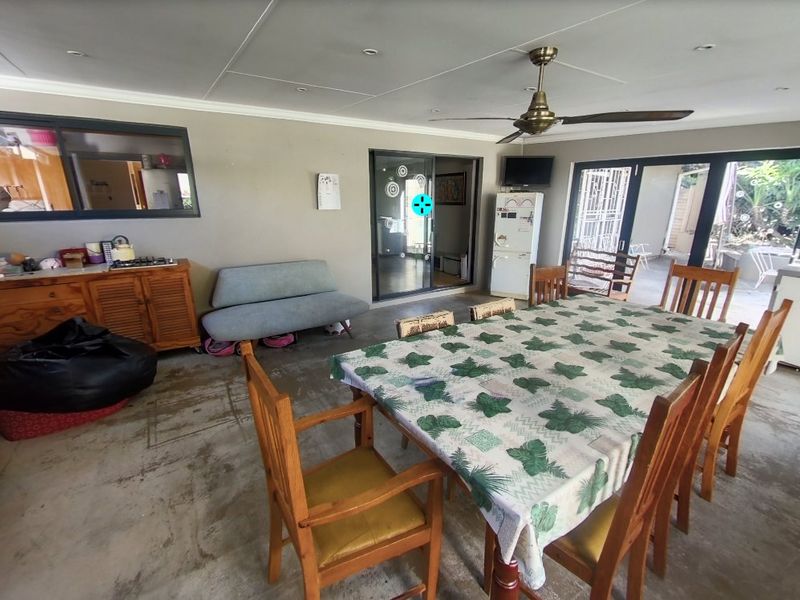 Open plan living and dining area featuring concrete flooring, ceiling fan, and large sliding glass doors providing access to the outdoor space.