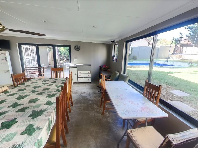 Spacious open-plan living area featuring large sliding glass doors and expansive windows providing views of the garden and pool area.