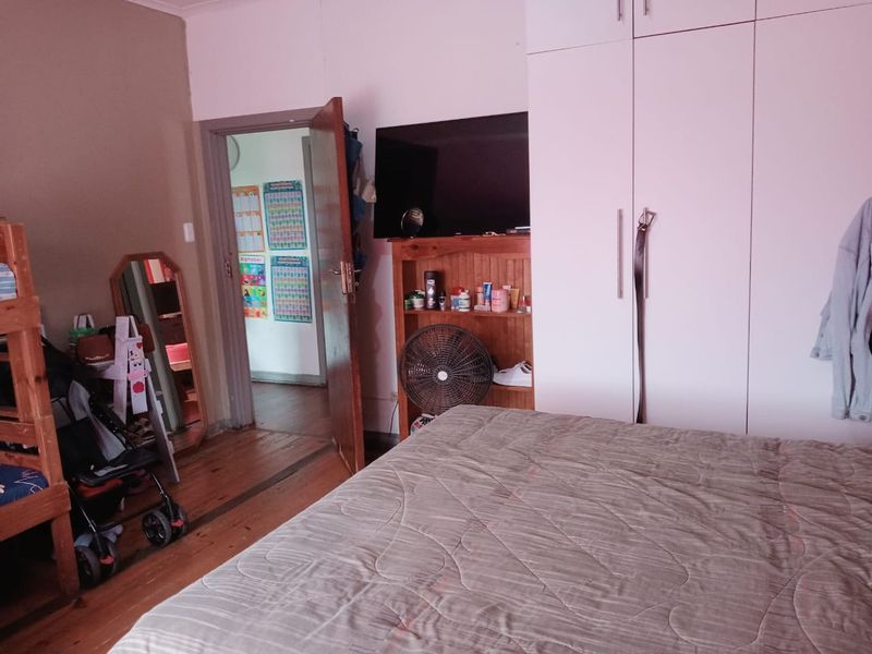 Bedroom featuring timber flooring and built-in cupboards, offering a functional space with potential for cosmetic updates.