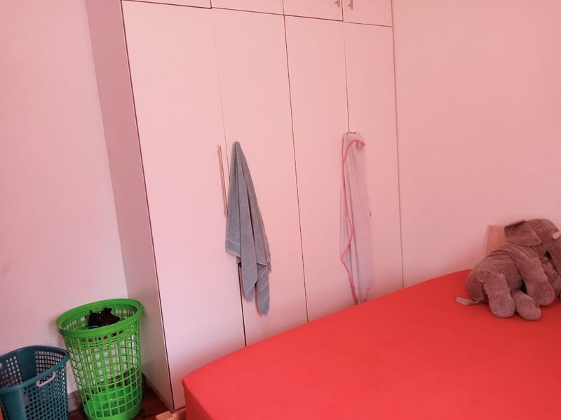 A bedroom featuring a large white built-in wardrobe with multiple doors, providing ample storage space.