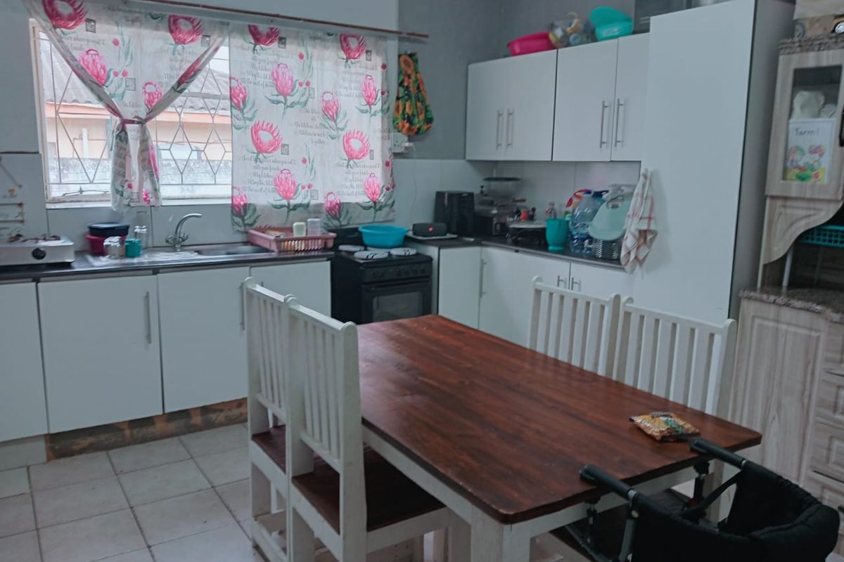 A functional kitchen featuring white cabinetry, a stainless steel sink, and tiled flooring, providing a practical space for meal preparation.