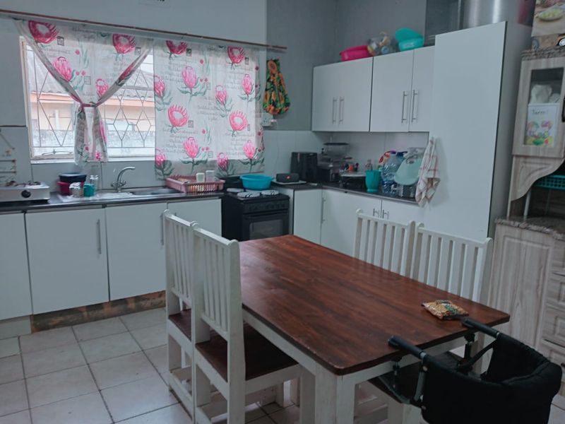 A functional kitchen featuring white cabinetry, a stainless steel sink, and tiled flooring, providing a practical space for meal preparation.