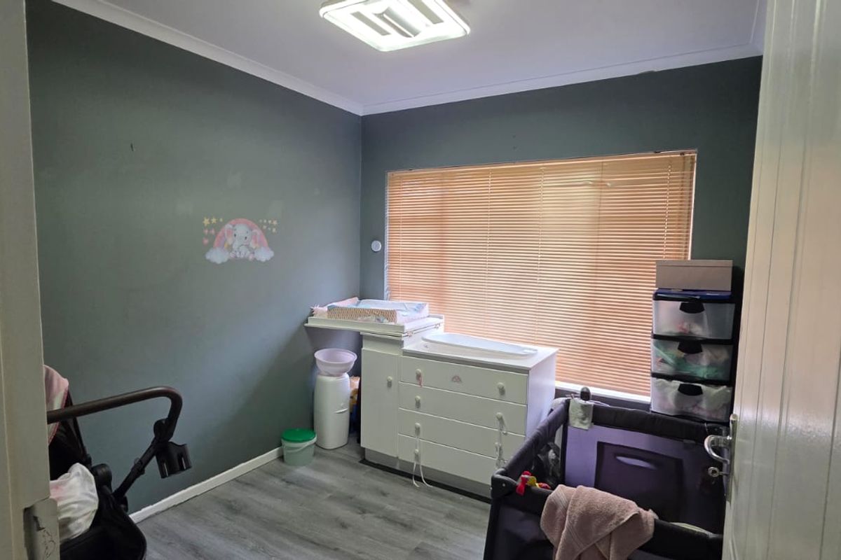 A bedroom featuring laminate flooring, venetian blinds, and cove cornicing, currently utilized as a nursery space.
