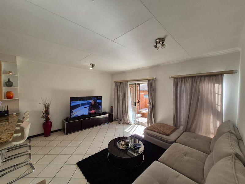 Open-plan living area featuring tiled flooring, a breakfast bar, and sliding glass doors providing access to the outdoor space.