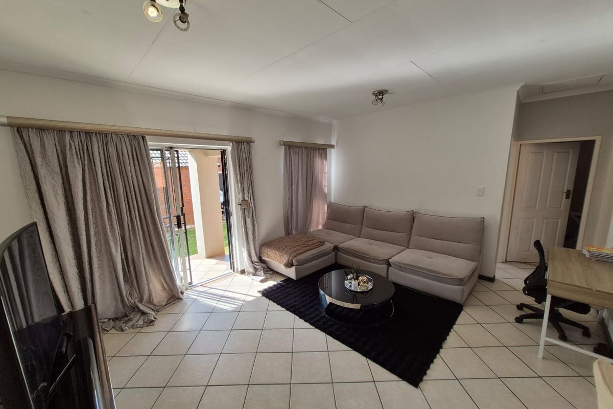 A bright living room featuring tiled flooring and a large sliding glass door providing access to the outdoor area.