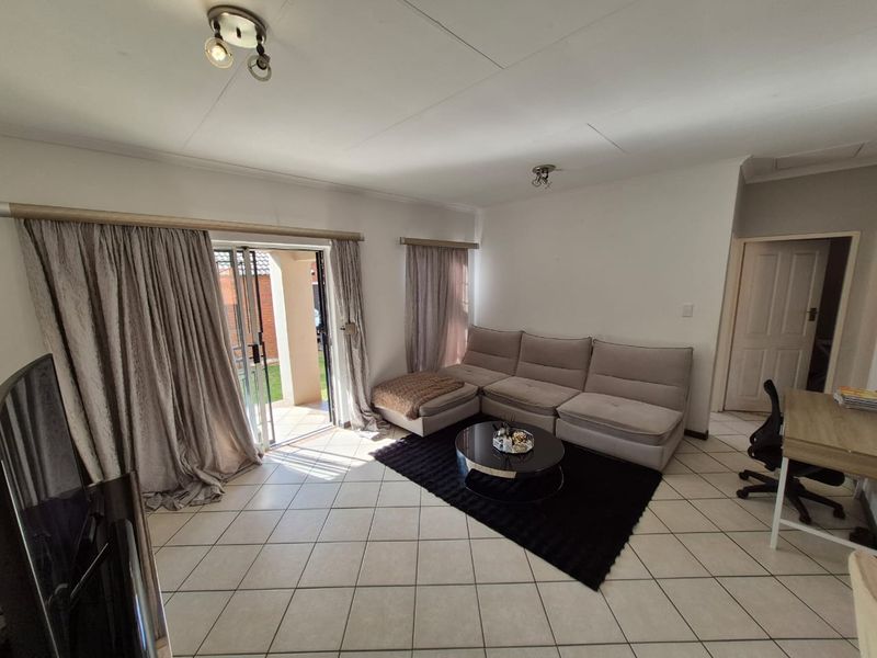 A bright living room featuring tiled flooring and a large sliding glass door providing access to the outdoor area.