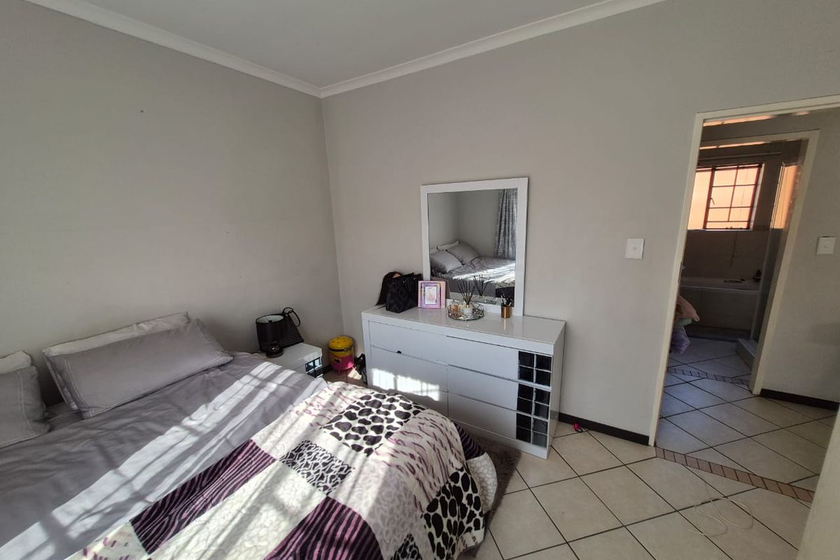 A bedroom featuring tiled flooring and coved ceilings, with an adjoining doorway leading to an en-suite bathroom.