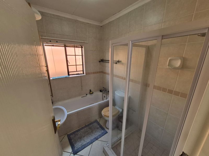 A functional bathroom featuring a bathtub, separate shower enclosure, and tiled finishes throughout, offering a practical layout for a townhouse.