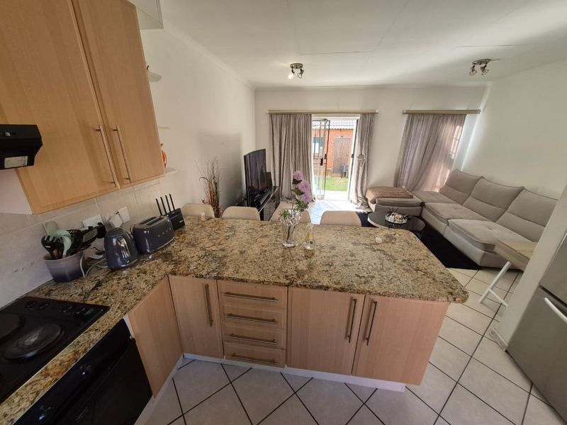 Open-plan living area featuring a kitchen with granite countertops and built-in appliances, flowing into a lounge with direct access to the rear garden.