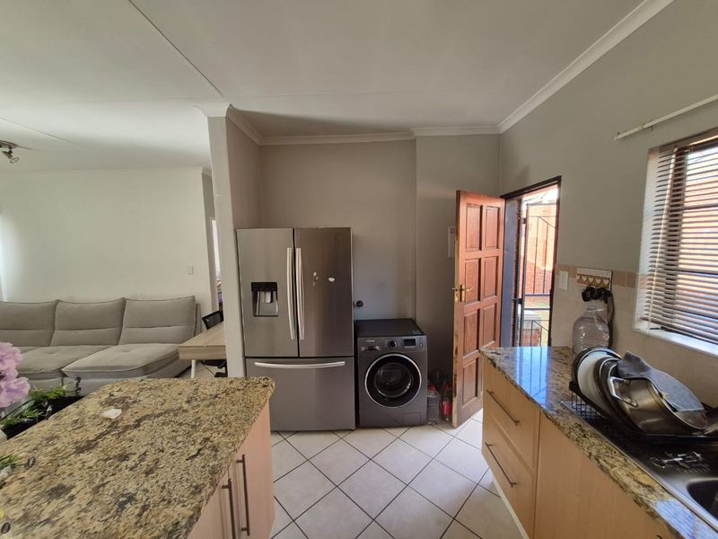 Open plan kitchen area featuring granite countertops, tiled flooring, and built-in cabinetry, with direct access to an exterior door.